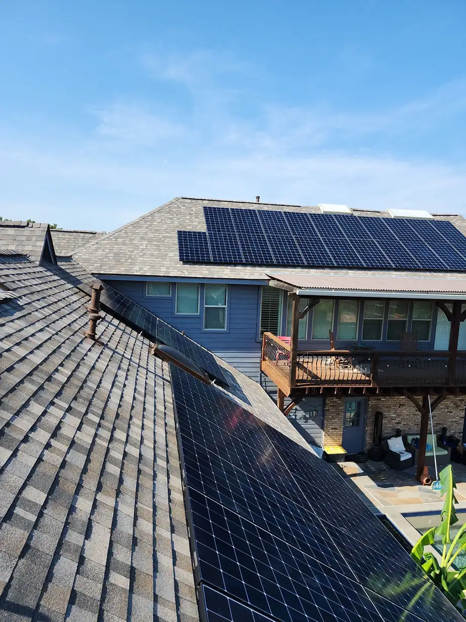 Residential house rooftops with solar panels installed under a clear blue sky.